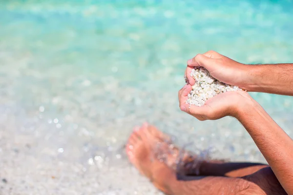 Mannelijke handen in de vorm van een hart met kiezels binnen op witte strand — Stockfoto