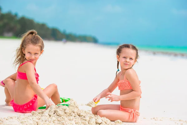 Niñas lindas jugando con juguetes de playa durante las vacaciones tropicales —  Fotos de Stock