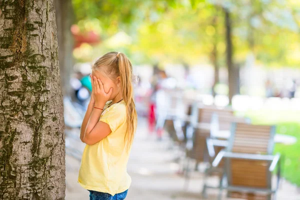 Милая девушка играет в прятки рядом с деревом в Париже — стоковое фото