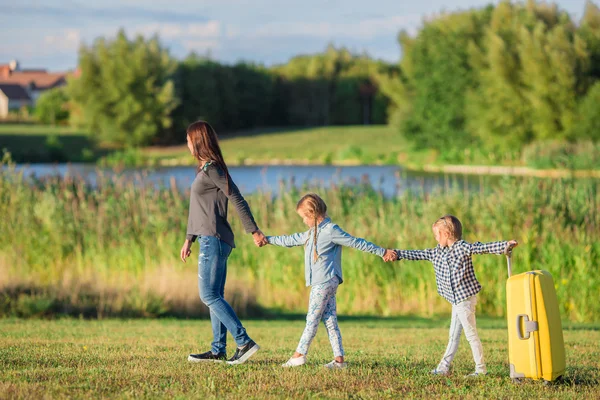 Happy family with suitcase walking outdoors — Stock Photo, Image