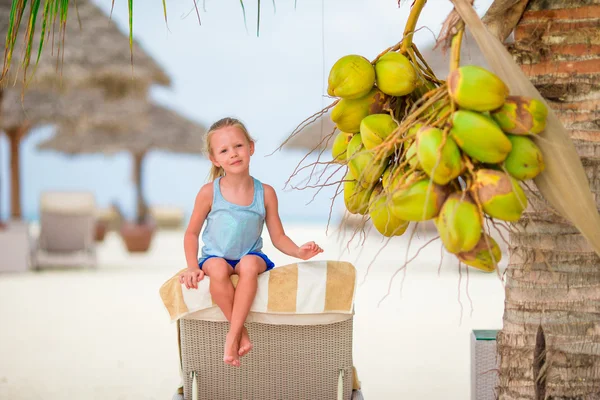 Little adorable girl near coconut on white tropical beach — Stock Photo, Image