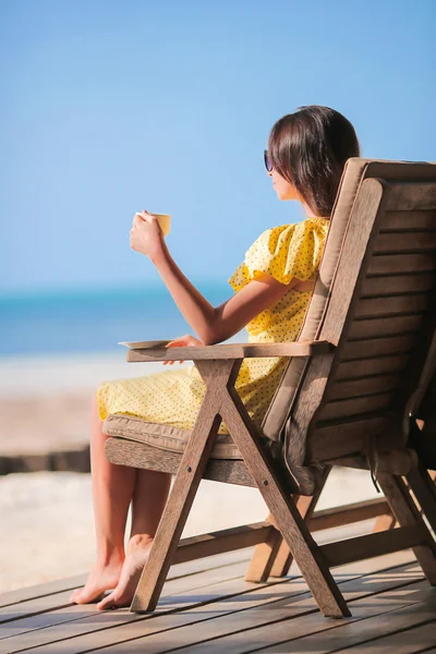 Mujer joven bebiendo café capuchino disfrutando de la vista a la playa — Foto de Stock