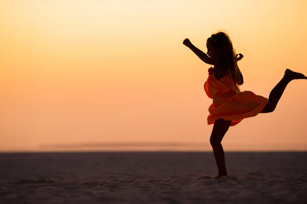 Silhouet van sportieve kleine meisje op de witte strand bij zonsondergang — Stockfoto