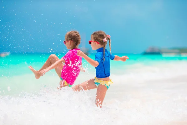 Le bambine si divertono sulla spiaggia tropicale durante le vacanze estive giocando insieme in acque poco profonde — Foto Stock