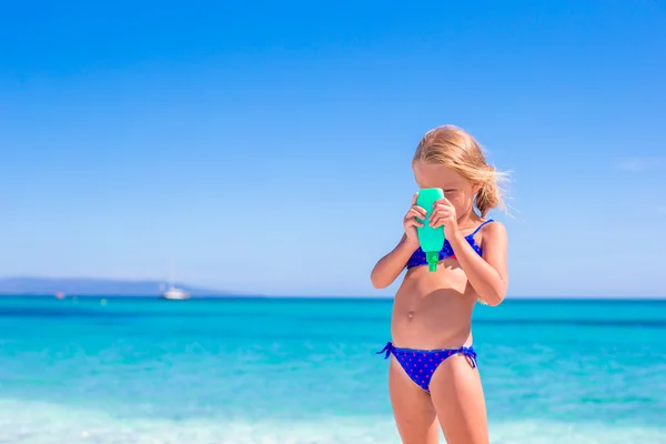 Schattig meisje met zonnebrand lotion fles op het strand — Stockfoto