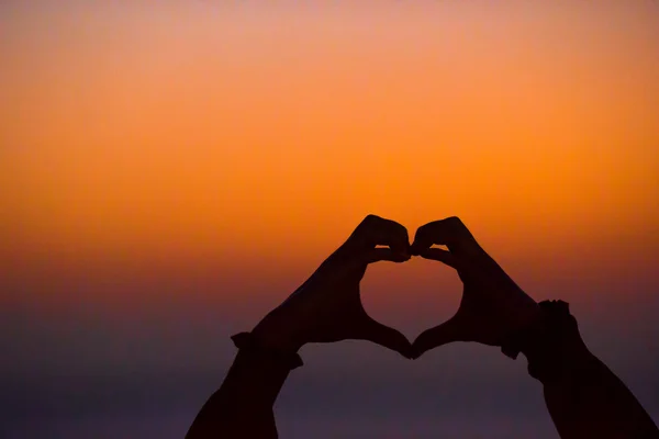 Silhueta de coração feito mãos ao pôr do sol — Fotografia de Stock