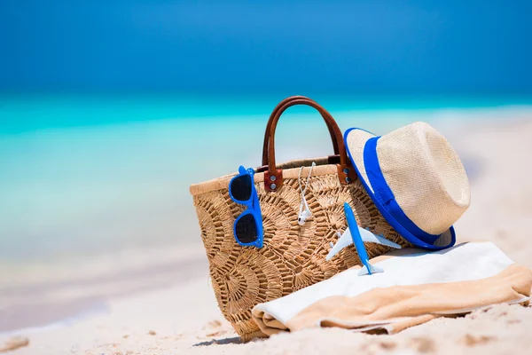 Beach consept - hasır çanta, şapka, güneş gözlüğü ve beyaz plajda havlu — Stok fotoğraf