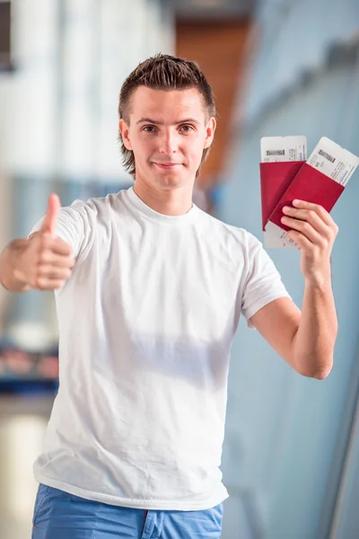 Junger Mann mit Pässen und Bordkarten im Flughafen — Stockfoto