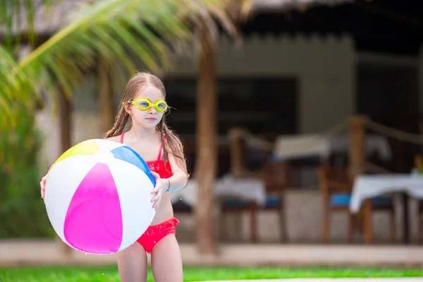 Menina adorável brincando com bola na piscina ao ar livre — Fotografia de Stock