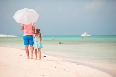 Plajda şemsiye ile ailesinin arkadan görünüm