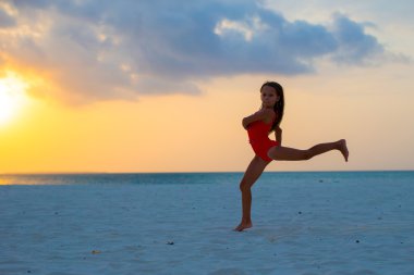 Gün batımında beyaz plaj üzerinde etkin sevimli küçük kız silüeti