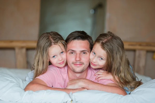 Father with two adorable little girls having fun in bed smiling — Stock Photo, Image