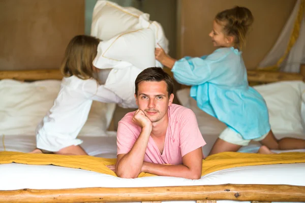 Niñas jugando en casa en la cama cerca de su padre —  Fotos de Stock