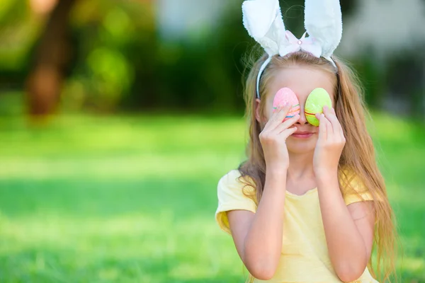 Adorable little girl wearing bunny ears with Easter eggs on spring day — Stock Photo, Image