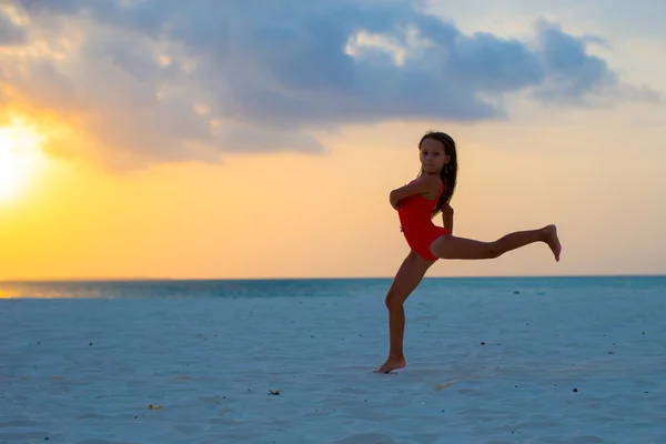 Silueta rozkošný aktivní holčička na bílé pláži při západu slunce — Stock fotografie