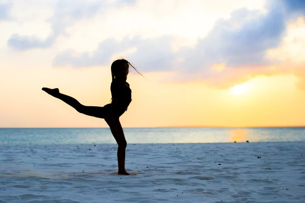 Actieve meisje springen op wit strand bij zonsondergang — Stockfoto