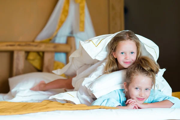 Adorable little girls having fun at bed inside — Stock Photo, Image