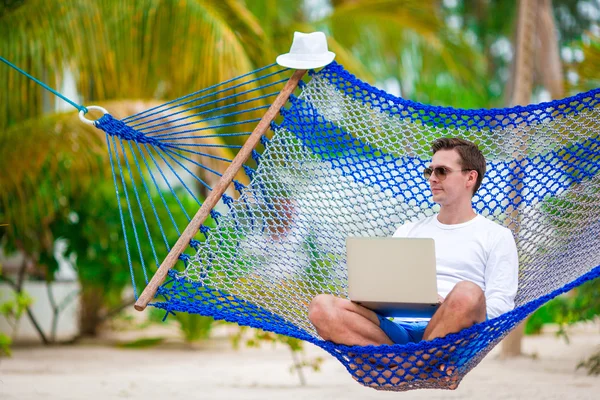 Mannen med laptop i hängmattan på tropiska semester — Stockfoto