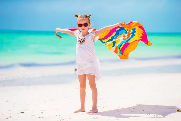 Little girl having fun running with towels on tropical beach — Stock Photo, Image