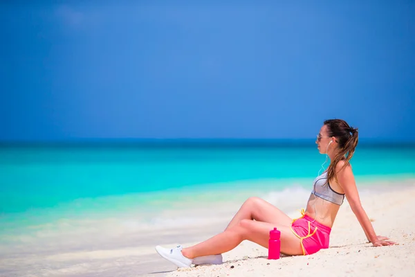 Fit jonge vrouw op tropische witte strand in haar sportkleding — Stockfoto