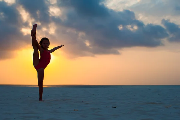 Silhueta de adorável menina ativa na praia branca ao pôr do sol — Fotografia de Stock