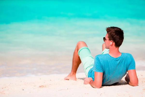 Joyeux jeune homme appréciant la musique sur la plage de sable blanc — Photo