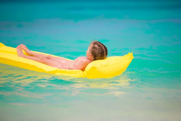 Adorabile bambina che si rilassa sui materassi sulla spiaggia bianca — Foto Stock