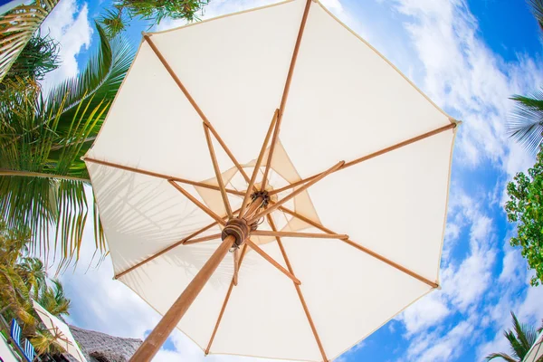 Ombrello bianco sfondo cielo blu sulla spiaggia tropicale bianca — Foto Stock