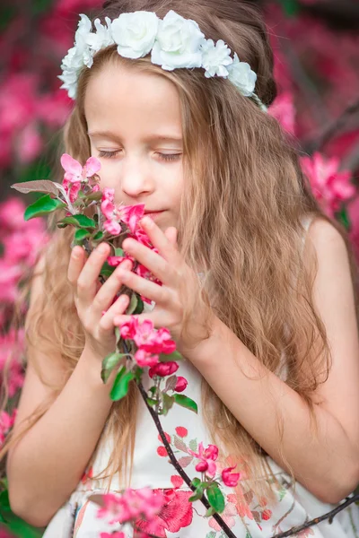 Adorável menina desfrutando cheiro em um jardim de primavera florido — Fotografia de Stock