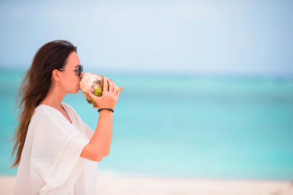 Mujer joven bebiendo leche de coco en la playa — Foto de Stock