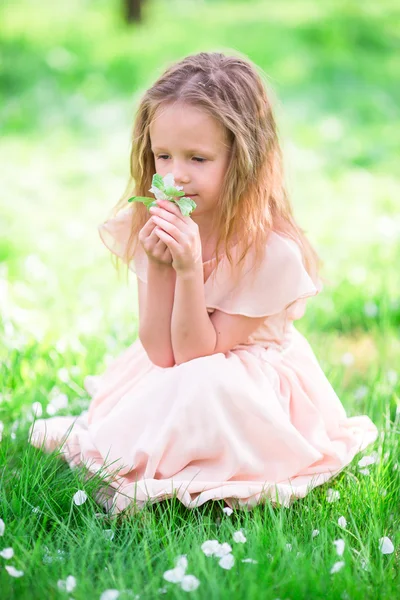 Adorable petite fille jouissant d'une odeur dans un jardin printanier fleuri — Photo