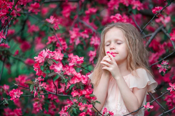 Αξιολάτρευτο κοριτσάκι να απολαύσετε μυρωδιά σε ένα κήπο άνοιξη ανθοφορία — Φωτογραφία Αρχείου