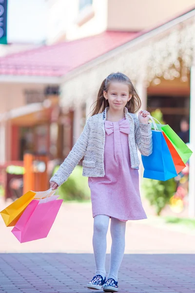 Bedårande liten flicka gå med shoppingkassar utomhus — Stockfoto