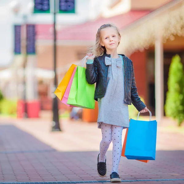 Adorable little girl walking with shopping bags outdoors — Stock Photo, Image