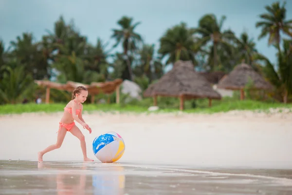 Little girl playing with big air ball on white beach