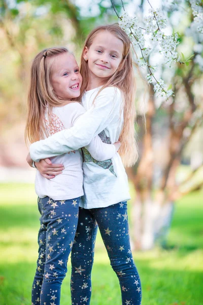 Adorables niñas en el jardín de cerezo en flor en el día de primavera — Foto de Stock