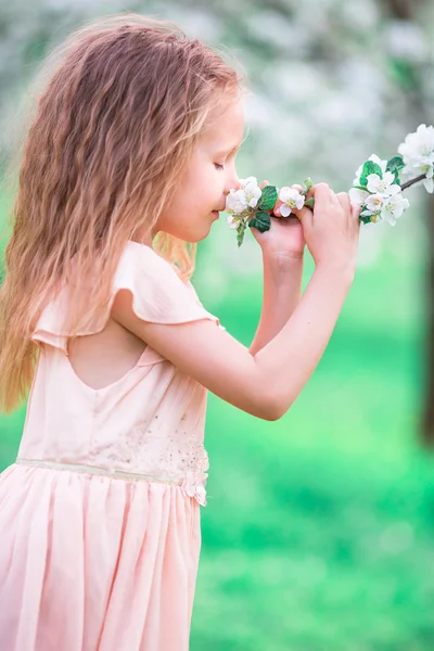 Adorable petite fille jouissant d'une odeur dans un jardin de printemps de cerise en fleurs — Photo