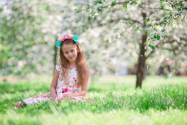 Kleines Mädchen im blühenden Kirschbaumgarten im Freien — Stockfoto