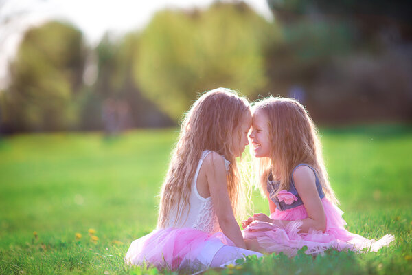 Adorable little girls in blooming cherry garden on beautiful spring day
