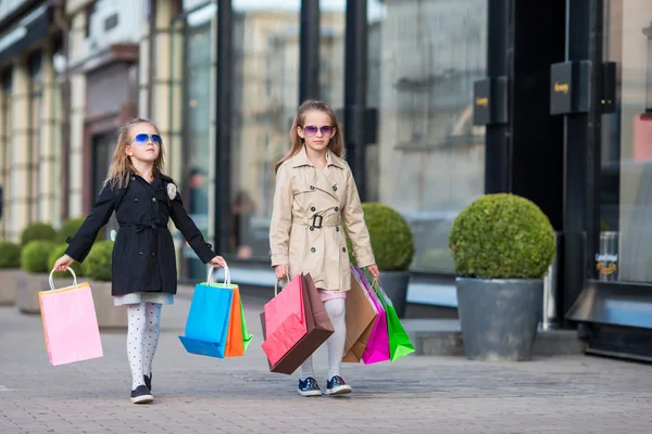 Adorables niñas con bolsas de compras caminando en la ciudad al aire libre — Foto de Stock