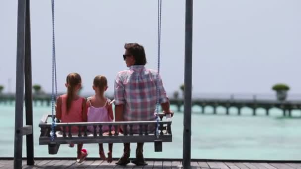 Adorables niñas y padre joven en swing — Vídeo de stock