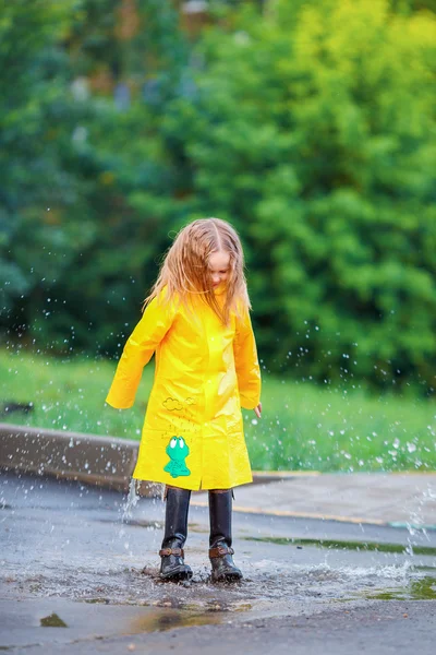 Menina em capa de chuva e botas jogando na chuva ao ar livre — Fotografia de Stock