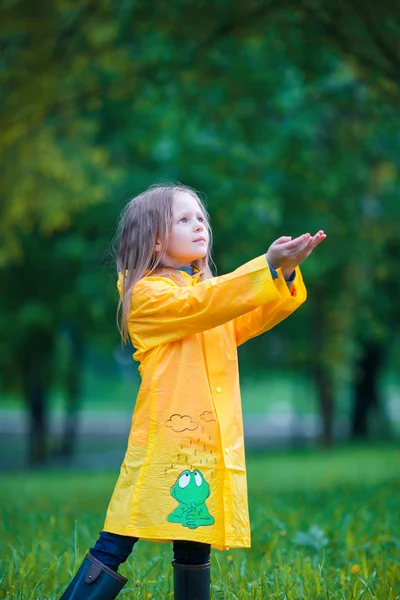 Adorable toddler girl wearing waterproof coat playing outdoors by rainy and sunny day — Stock Photo, Image