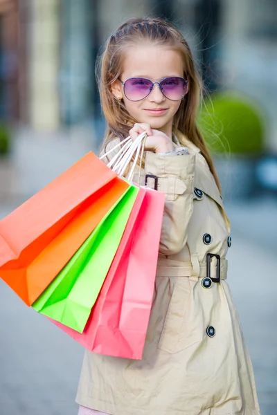 Sevimli küçük kız ile alışveriş torbaları açık havada yürüyüş portresi — Stok fotoğraf