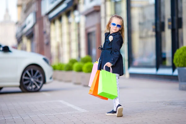 Чарівна маленька дівчинка гуляє з сумками на відкритому повітрі — стокове фото