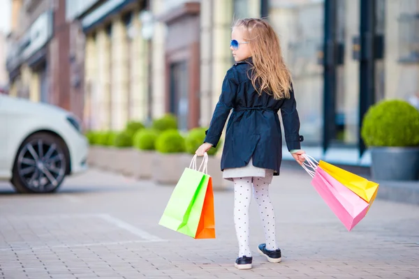Schattig meisje plezier met boodschappentassen outdoors — Stockfoto