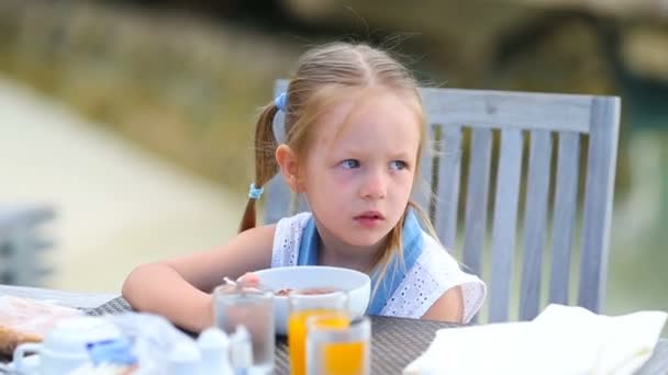 Söt liten flicka som äter frukost på uteservering — Stockvideo