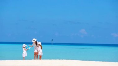 Beyaz elbiseli ailenin yaz tatilinin tadını çıkardığı güzel bir tropikal plaj manzarası.