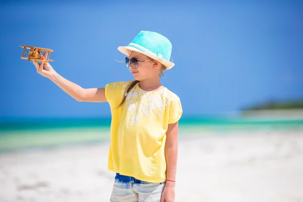 Menina feliz com brinquedo avião em mãos na praia de areia branca — Fotografia de Stock