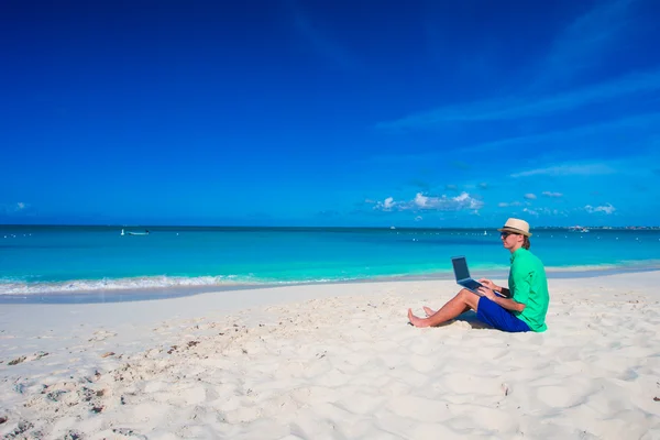 Молодой человек с планшетным компьютером и мобильным телефоном на тропическом пляже — стоковое фото